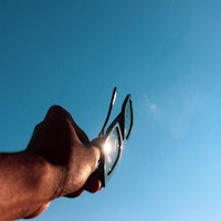 a person holding a pair of glasses up to the sky